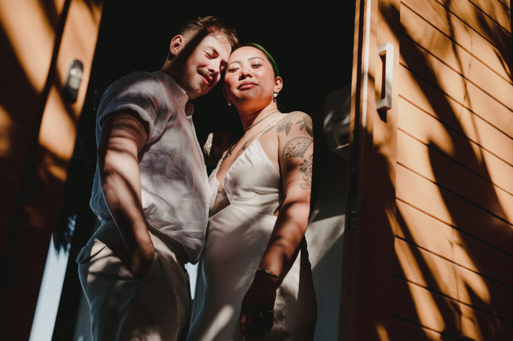 Couple in white embracing at Villa Amor Sayulita elopement, dappled sunlight and wood siding