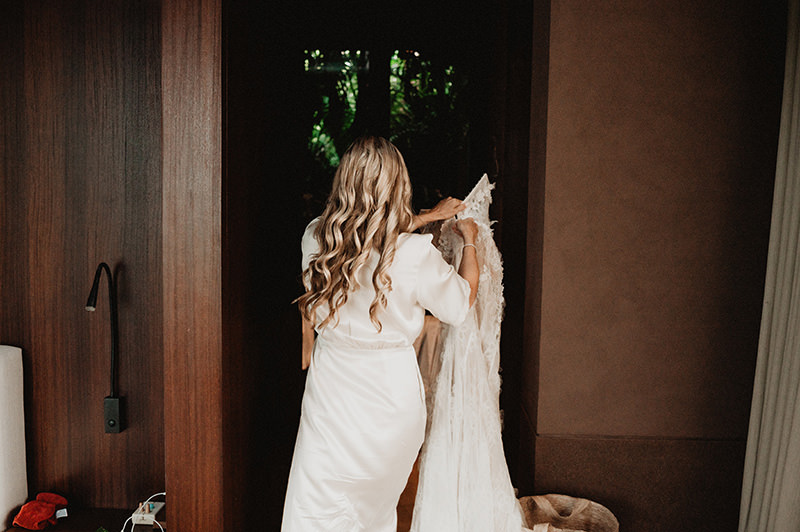 Bride in silk robe holding wedding dress at One&Only Mandarina, documentary wedding photography Mexico