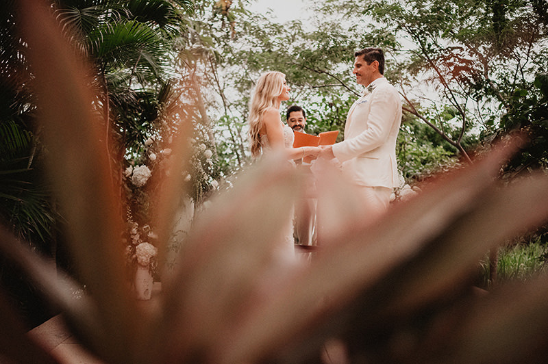 Wedding ceremony at One&Only Mandarina, couple exchanging vows surrounded by tropical jungle foliage
