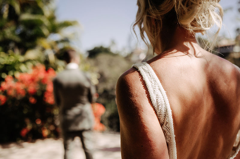 Bride in backless gown approaches groom at Villa Amor Sayulita wedding ceremony, tropical garden background