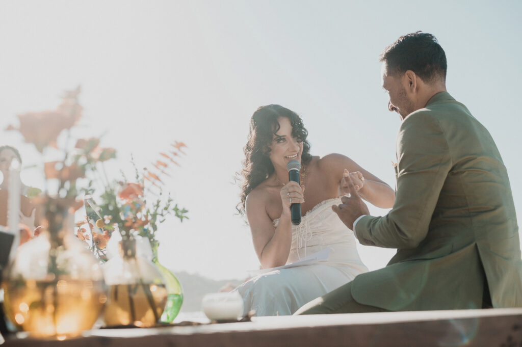 Bride reads vows with microphone at outdoor wedding ceremony, Frente al Punto Sayulita, warm golden light