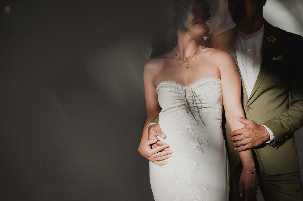 Bride in floral gown and groom in sage suit embrace at Frente al Punto, Sayulita wedding ceremony