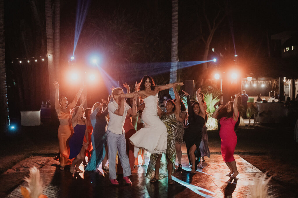 Bride lifted by groom on dance floor at night wedding reception, Frente al Punto, Sayulita