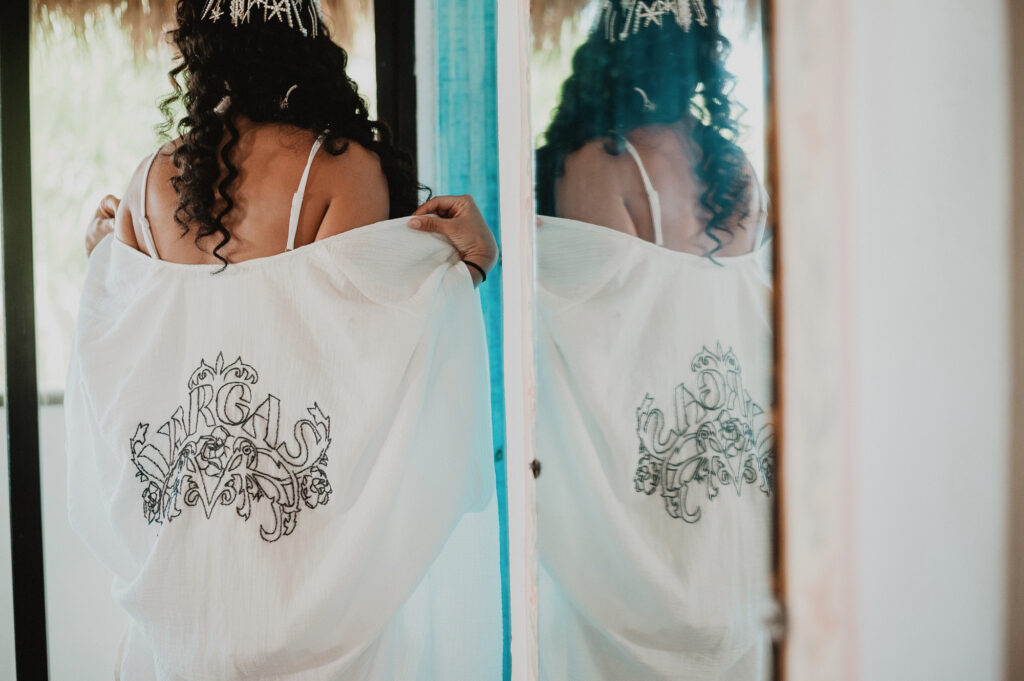 Bride holding embroidered robe with Vargas crest before wedding ceremony, Sayulita Mexico