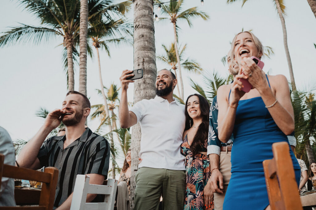 Wedding guests laughing and taking photos during reception at Frente al Punto, Sayulita Mexico