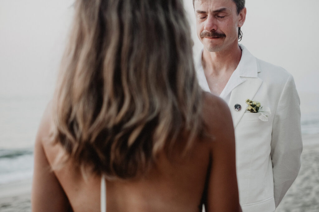 Groom in white suit crying during beach wedding ceremony at Villa del Sol Sayulita Mexico