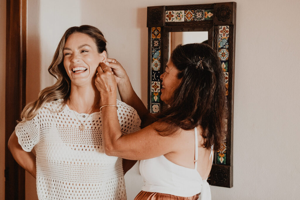 Bride laughing as someone helps her put on earrings before her wedding at Villa del Sol, Sayulita