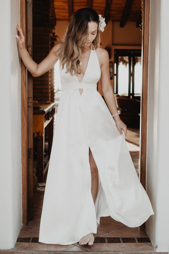 Bride in white halter gown with plunge neckline standing in wooden doorway at Villa del Sol Sayulita wedding