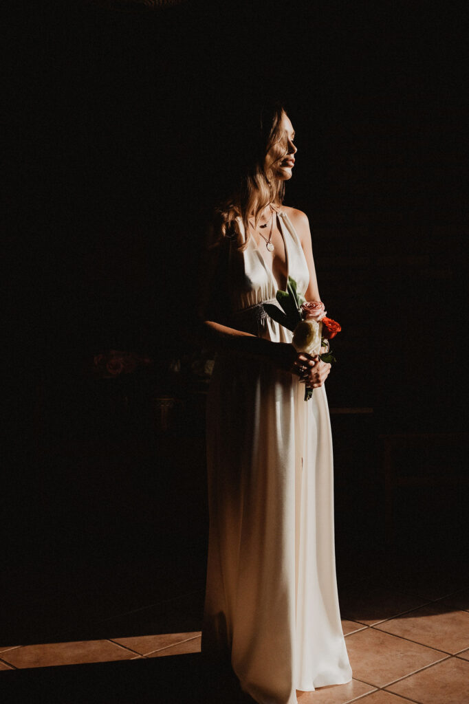 Bride in white halter gown holding roses, bathed in golden light at Villa del Sol, Sayulita wedding ceremony