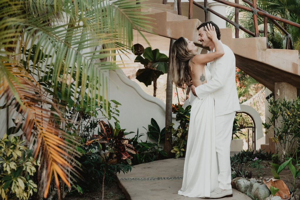 Couple embracing and laughing in tropical garden at Villa del Sol, Sayulita wedding ceremony