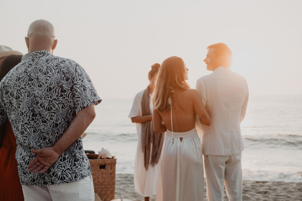 Beach wedding ceremony at sunset in Sayulita, couple standing with officiant near ocean waves