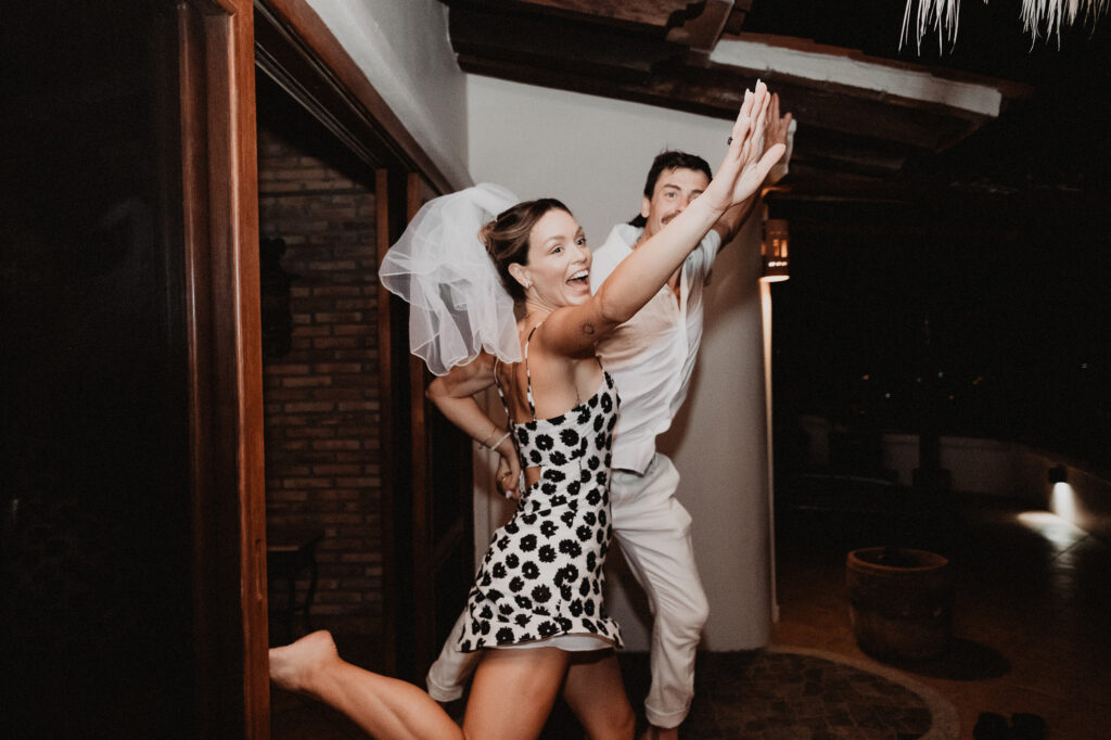 Bride in floral dress and veil dancing joyfully with groom at Villa del Sol Sayulita wedding reception