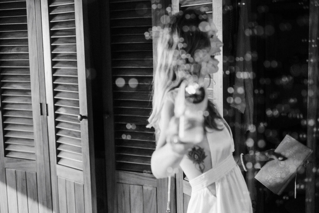 Bride laughing and holding champagne bottle at Villa del Sol, Sayulita wedding reception, black and white film style