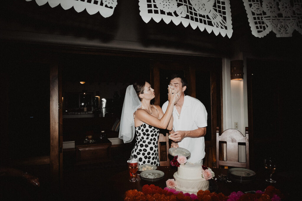 Bride smearing cake on groom's face at Villa del Sol reception, Sayulita wedding photography by Alex Obregón