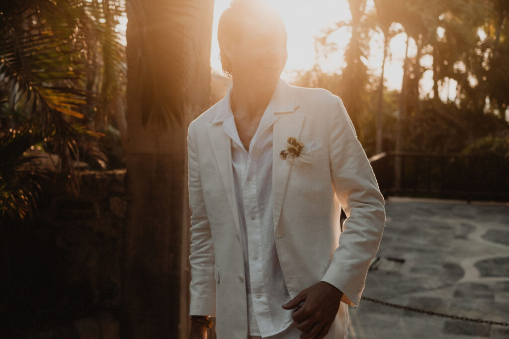 Groom in white linen suit at golden hour, Villa del Sol Sayulita wedding ceremony, boutonniere detail