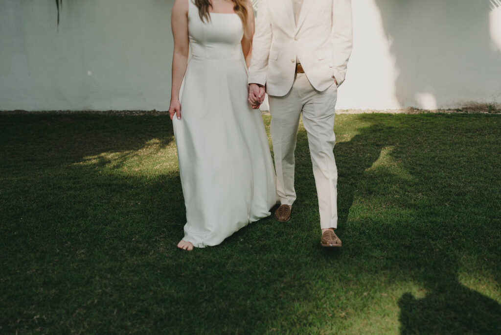 Bride and groom holding hands walking on grass at Frente al Punto Sayulita wedding