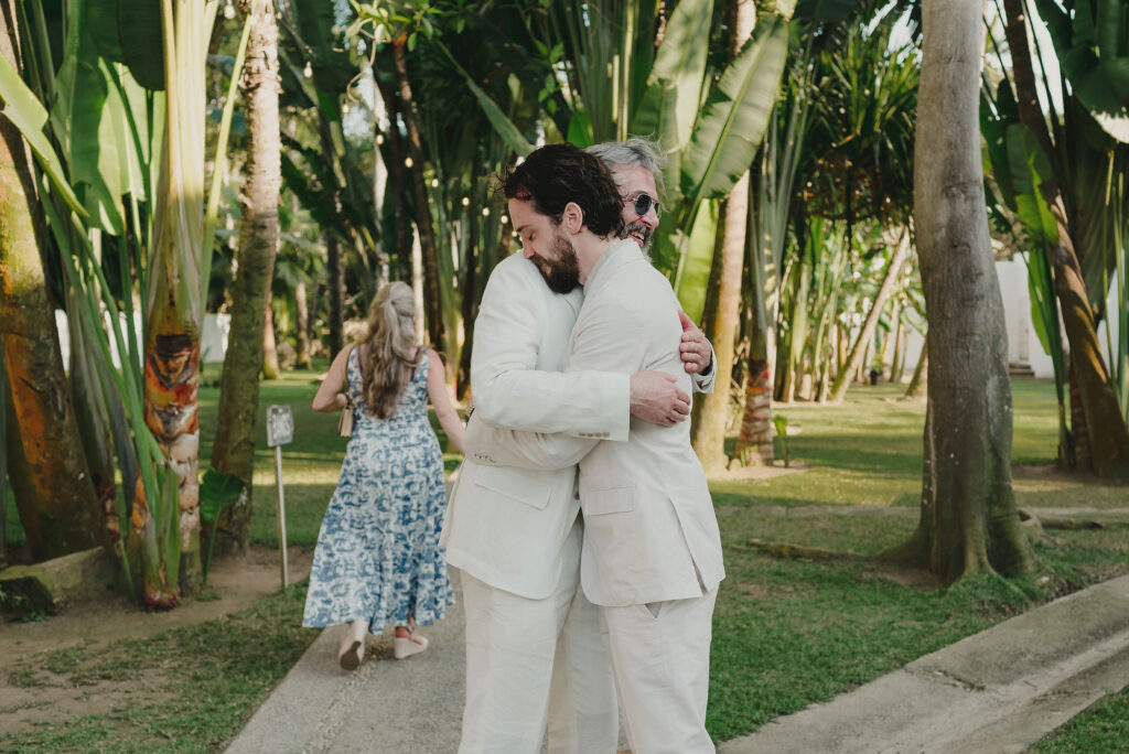 Two grooms hugging at outdoor wedding ceremony at Frente al Punto, Sayulita, Mexico