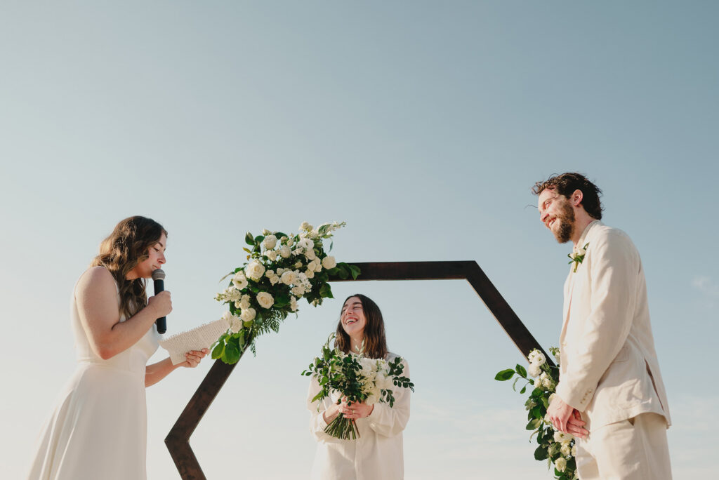 Wedding ceremony at Frente al Punto Sayulita with bride laughing under hexagonal arch, white roses