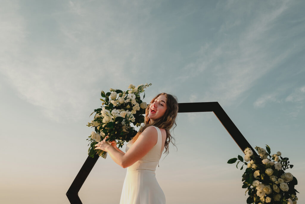 Bride laughing with white bouquet at hexagonal arch, Sayulita wedding ceremony by Alex Obregón