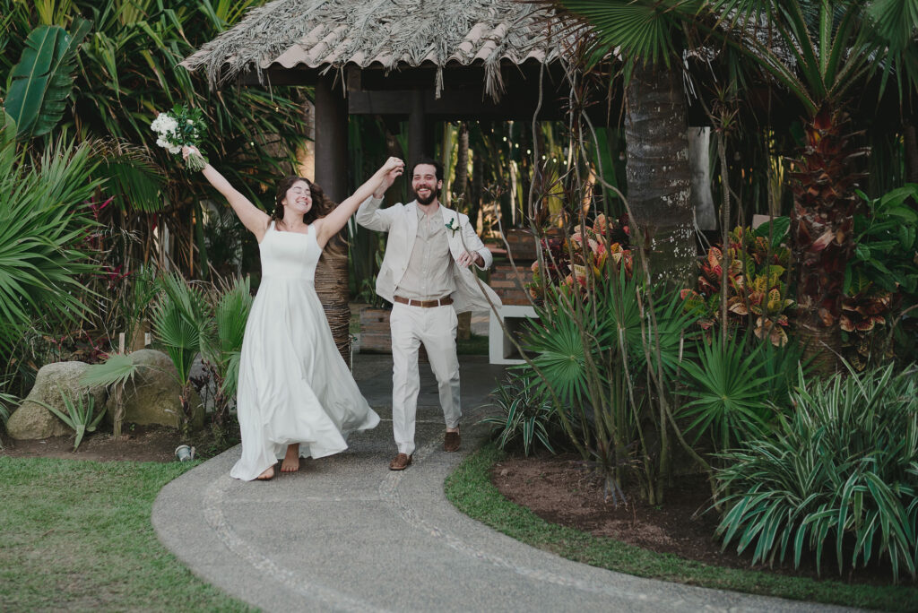 Bride and groom celebrating joyfully at Frente al Punto, Sayulita wedding ceremony, tropical garden backdrop