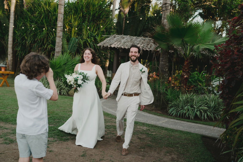 Bride and groom walk hand in hand laughing at outdoor wedding reception, Frente al Punto, Sayulita