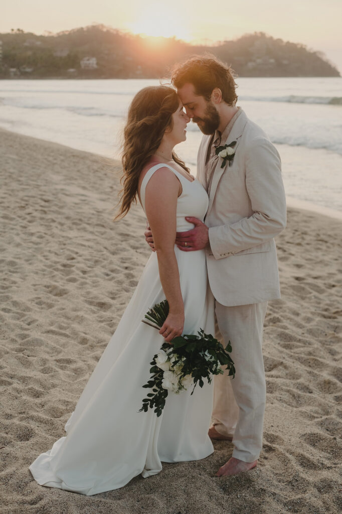 Bride and groom share a romantic sunset moment on the beach in Sayulita, Mexico, during their wedding ceremony
