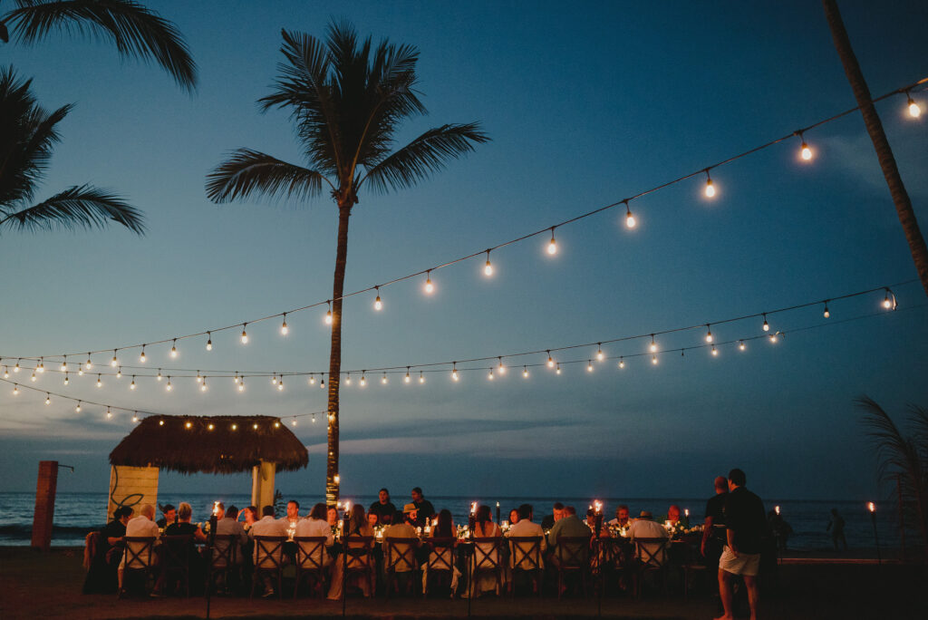 Beach wedding reception at dusk with string lights and palm trees at Frente al Punto, Sayulita, Mexico