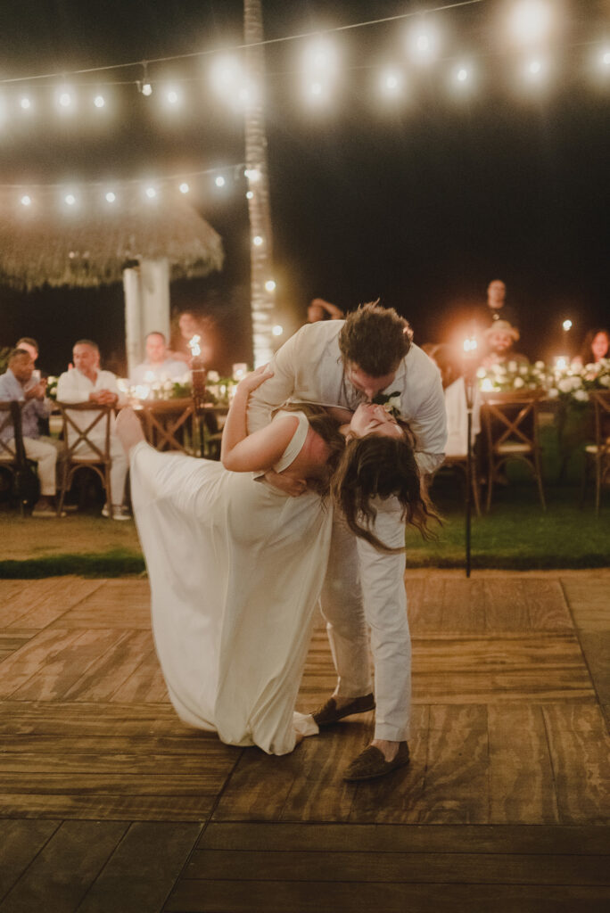 Bride and groom share a romantic dip kiss on the dance floor at a Sayulita wedding reception under string lights