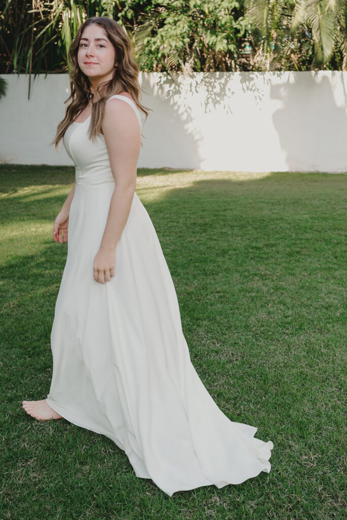 Bride in flowing white gown walking barefoot on green lawn at Frente al Punto, Sayulita wedding ceremony
