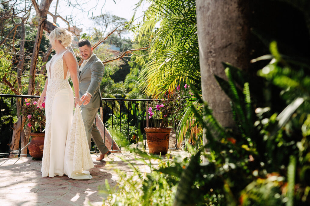 Groom smiling as he carries bride's train on terrace at Villa Amor Sayulita wedding
