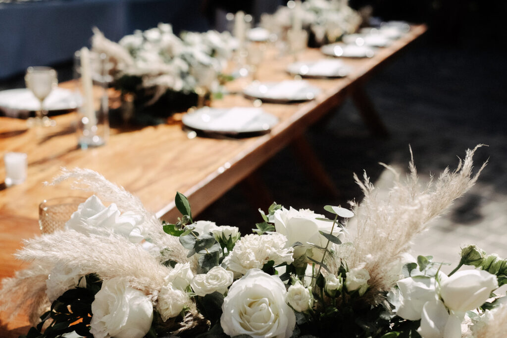 White roses and pampas grass table runner at Villa Amor Sayulita wedding reception on wood farm table