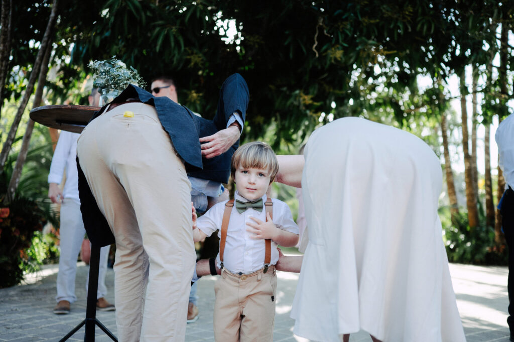 Ring bearer in suspenders and bow tie stands between wedding guests at Villa Amor Sayulita ceremony