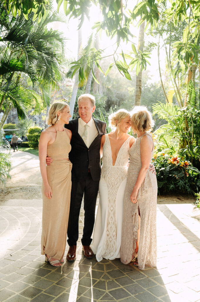 Family portrait at Villa Amor Sayulita wedding, bride in white gown with father and two sisters in golden dresses