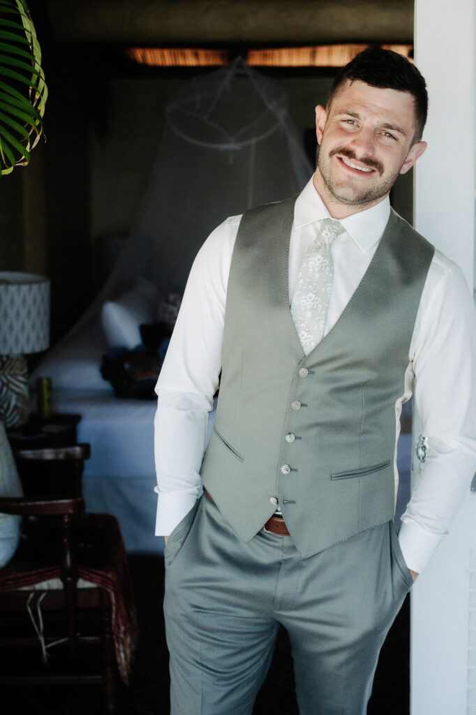 Groom smiling in sage green vest and floral tie at Villa Amor Sayulita wedding, documentary style