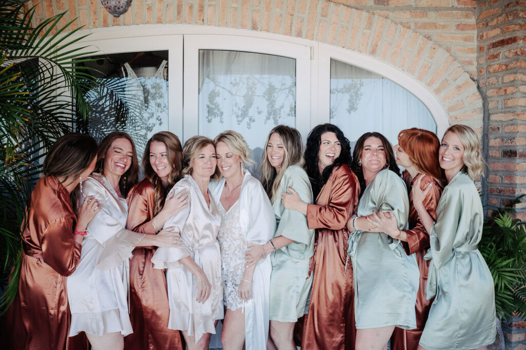 Bride and bridesmaids in satin robes laughing together before wedding ceremony at Villa Amor, Sayulita