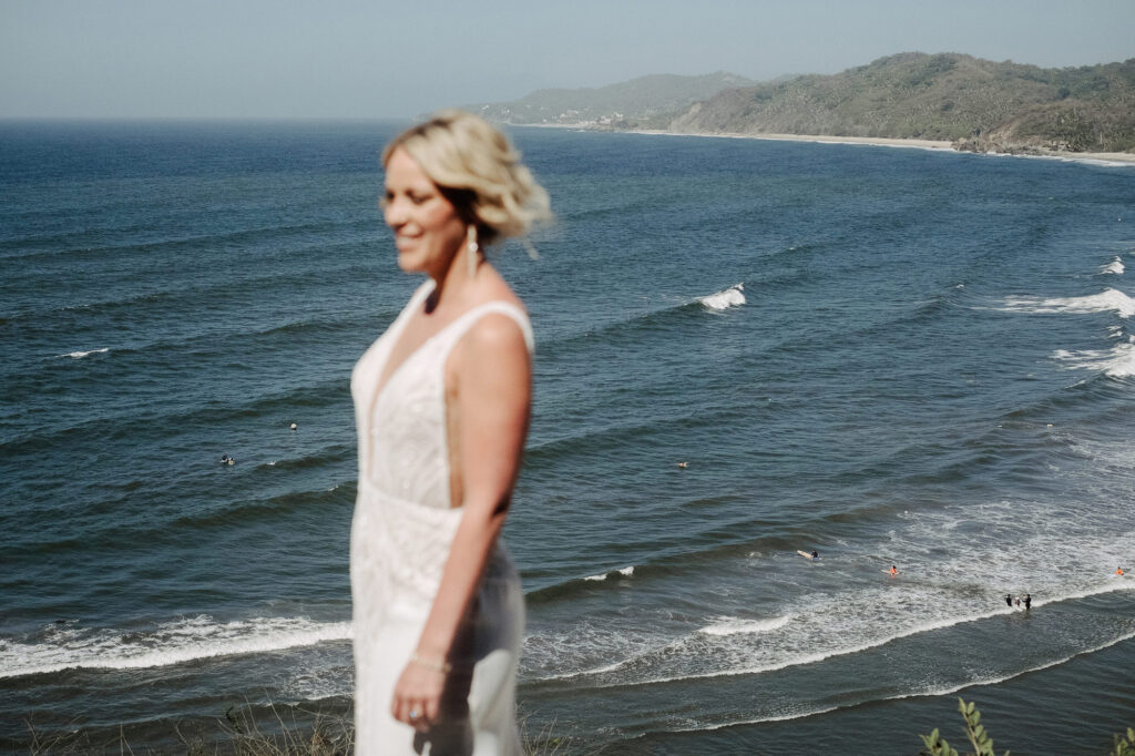 Bride smiling in white gown overlooking ocean waves at Villa Amor, Sayulita wedding