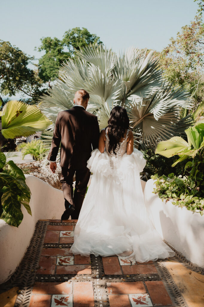 Bride and groom walking up tiled steps at Villa Valentin Sayulita, surrounded by tropical palms