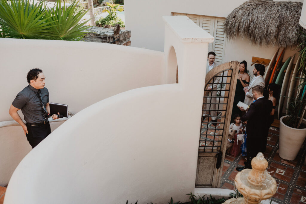 Wedding ceremony guests gathered at Villa Valentin gate in Sayulita, Mexico, with DJ holding equipment nearby
