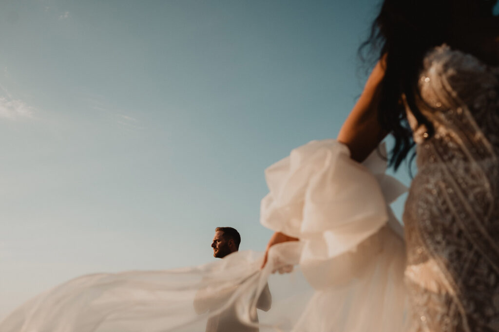 Bride's flowing white gown billows in the wind at Villa Valentin Sayulita wedding ceremony, groom smiling in background