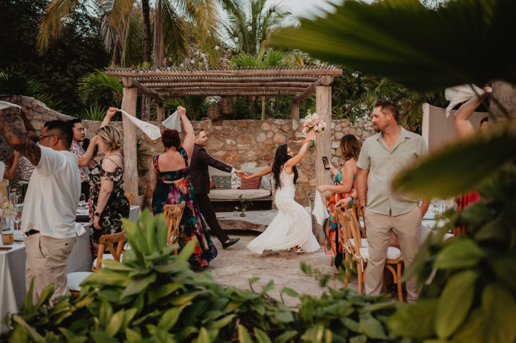 Bride and groom dance entrance with guests waving napkins at Villa Valentin wedding reception in Sayulita Mexico