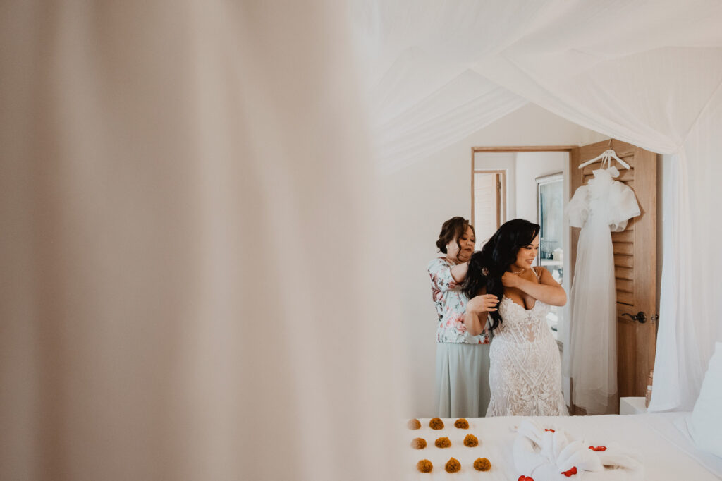 Bride getting ready in lace gown at Villa Valentin Sayulita, assisted by loved one before wedding ceremony