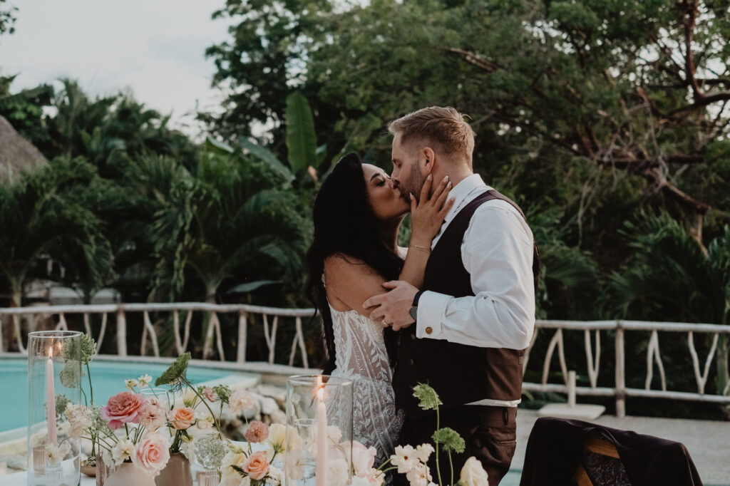 Bride and groom share a kiss at candlelit reception table, Villa Valentin, Sayulita wedding