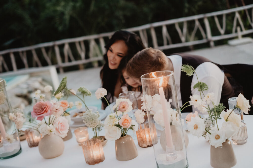 Wedding reception table with candles and blush flowers at Villa Valentin Sayulita, guests in background