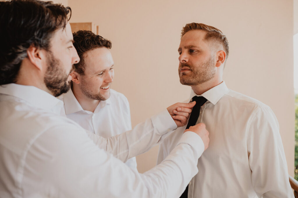 Groomsmen helping groom adjust his tie before wedding ceremony at Villa Valentin Sayulita Mexico
