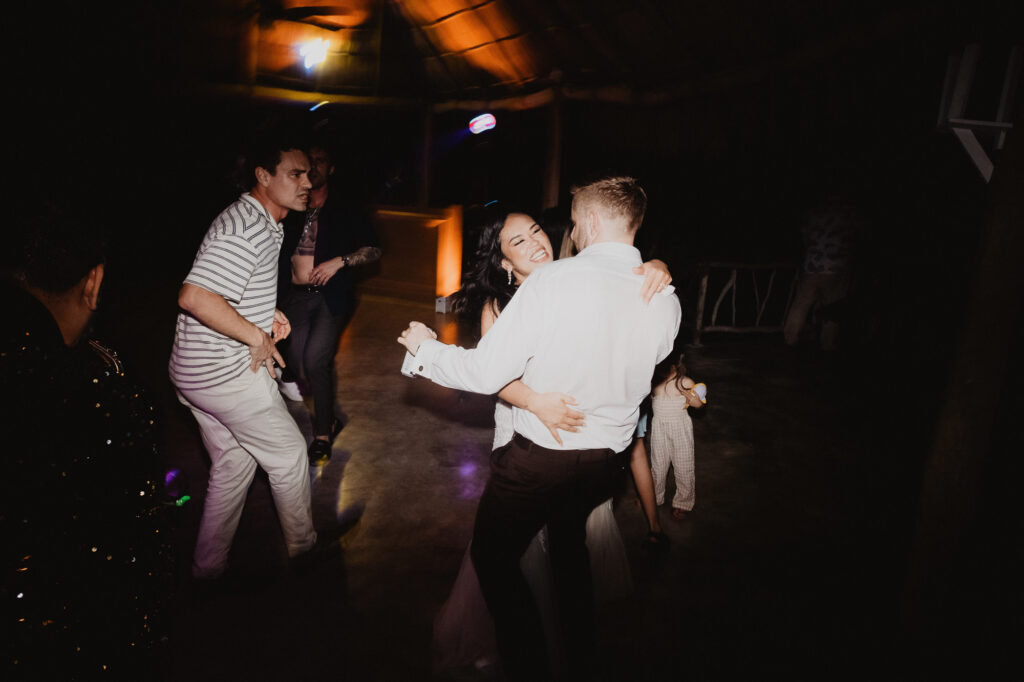 Couple dancing joyfully at wedding reception, Villa Valentin Sayulita, surrounded by guests on dance floor