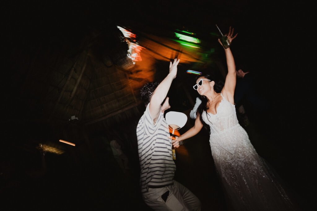Bride in white gown and sunglasses dancing with guest at Villa Valentin wedding reception, Sayulita
