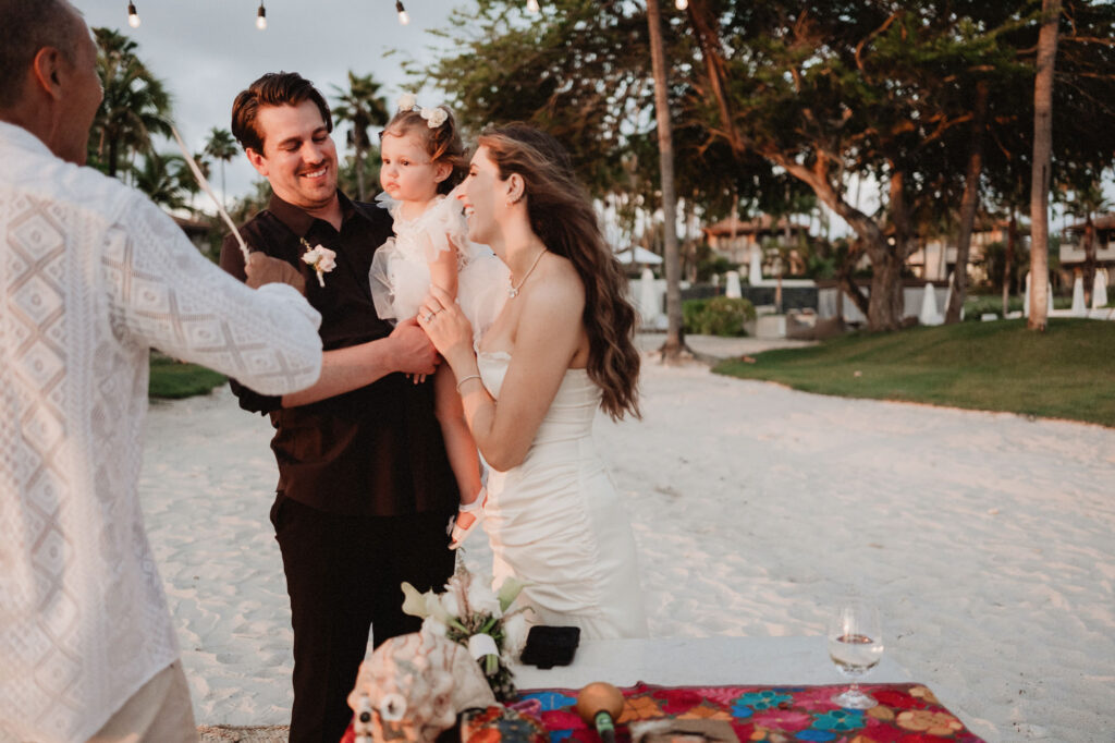 Bride and groom holding their daughter during beach elopement ceremony at St Regis Punta Mita Mexico