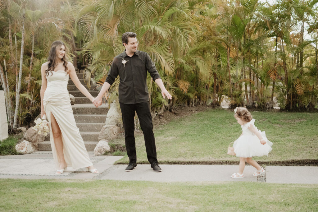 Bride and groom hold hands with flower girl at St Regis Punta Mita elopement wedding, tropical garden backdrop