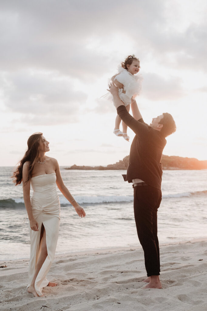 Elopement couple lifting toddler on Punta Mita beach at golden hour, St Regis, Mexico