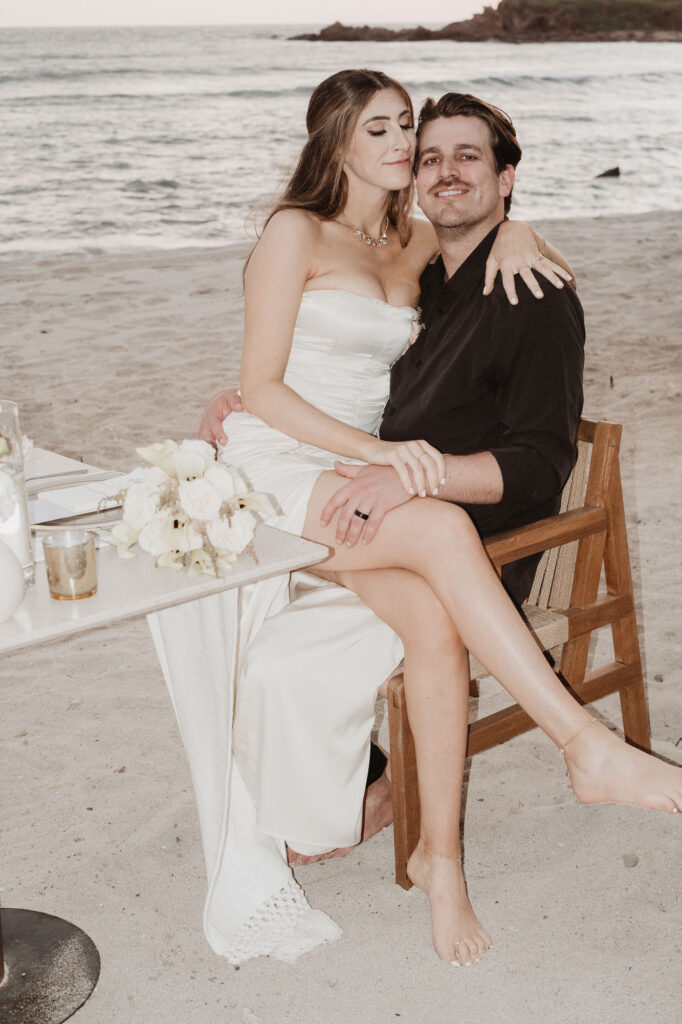 Bride and groom embracing at beach sweetheart table during Punta Mita elopement at St Regis